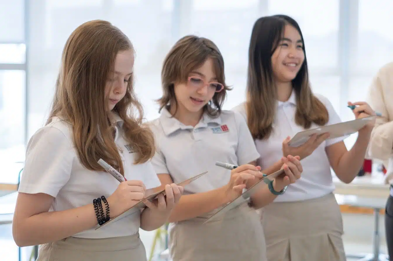 Three secondary school students at Hong Kong Academy collaborating on an inquiry-based project using clipboards at our award-winning Sai Kung campus.