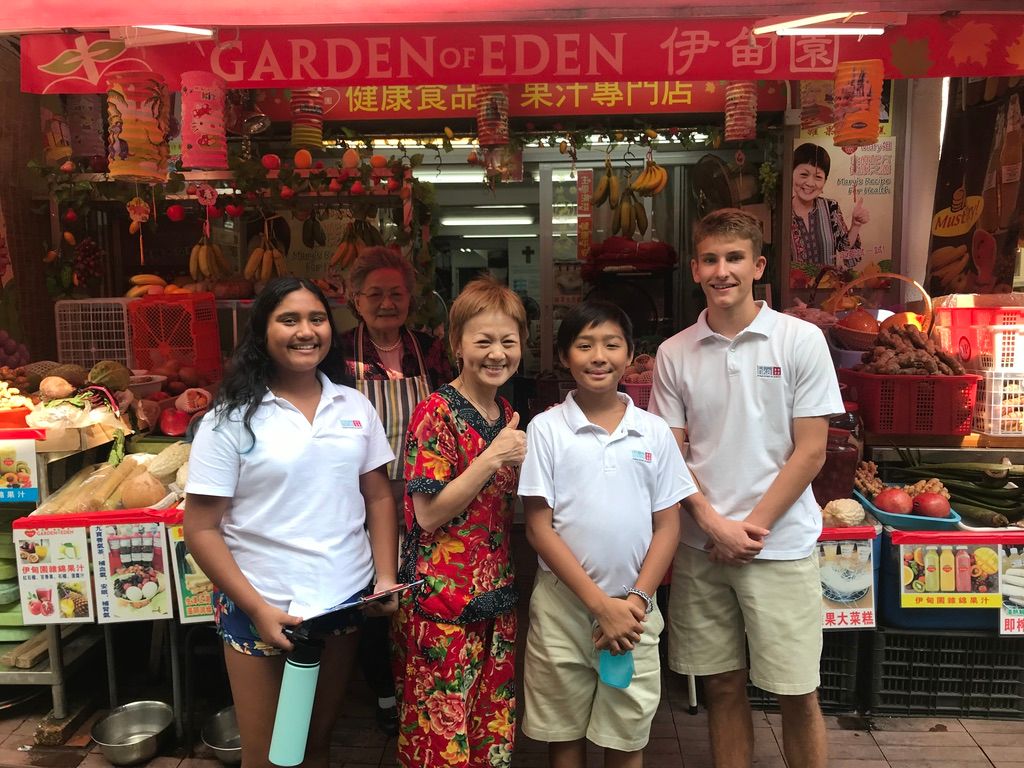 Students taking photos in front of the Garden Eden shop with owners