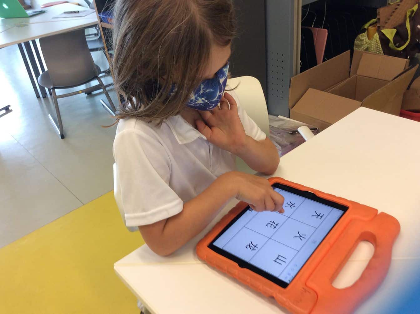 An HKA student using educational technology and an iPad to engage with Chinese characters, demonstrating student-centered digital learning at our school.