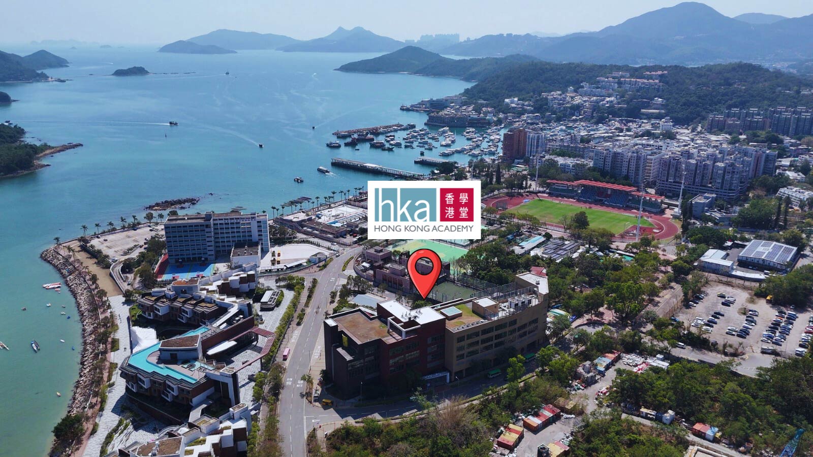 Families and students celebrating cultural diversity at a Hong Kong Academy community event featuring international flags and food stalls in our Sai Kung campus atrium.